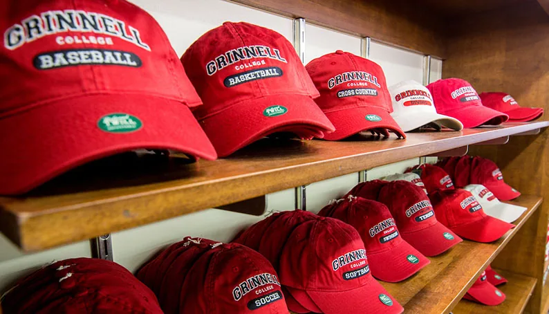 A line of red sport-specific Grinnell caps on a display rack.